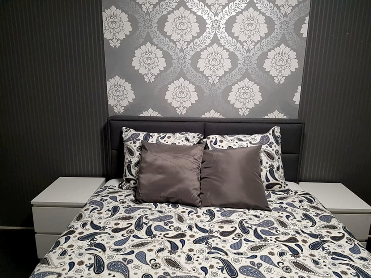 Furnished bedroom with double bed, patterned bedding and two bedside tables