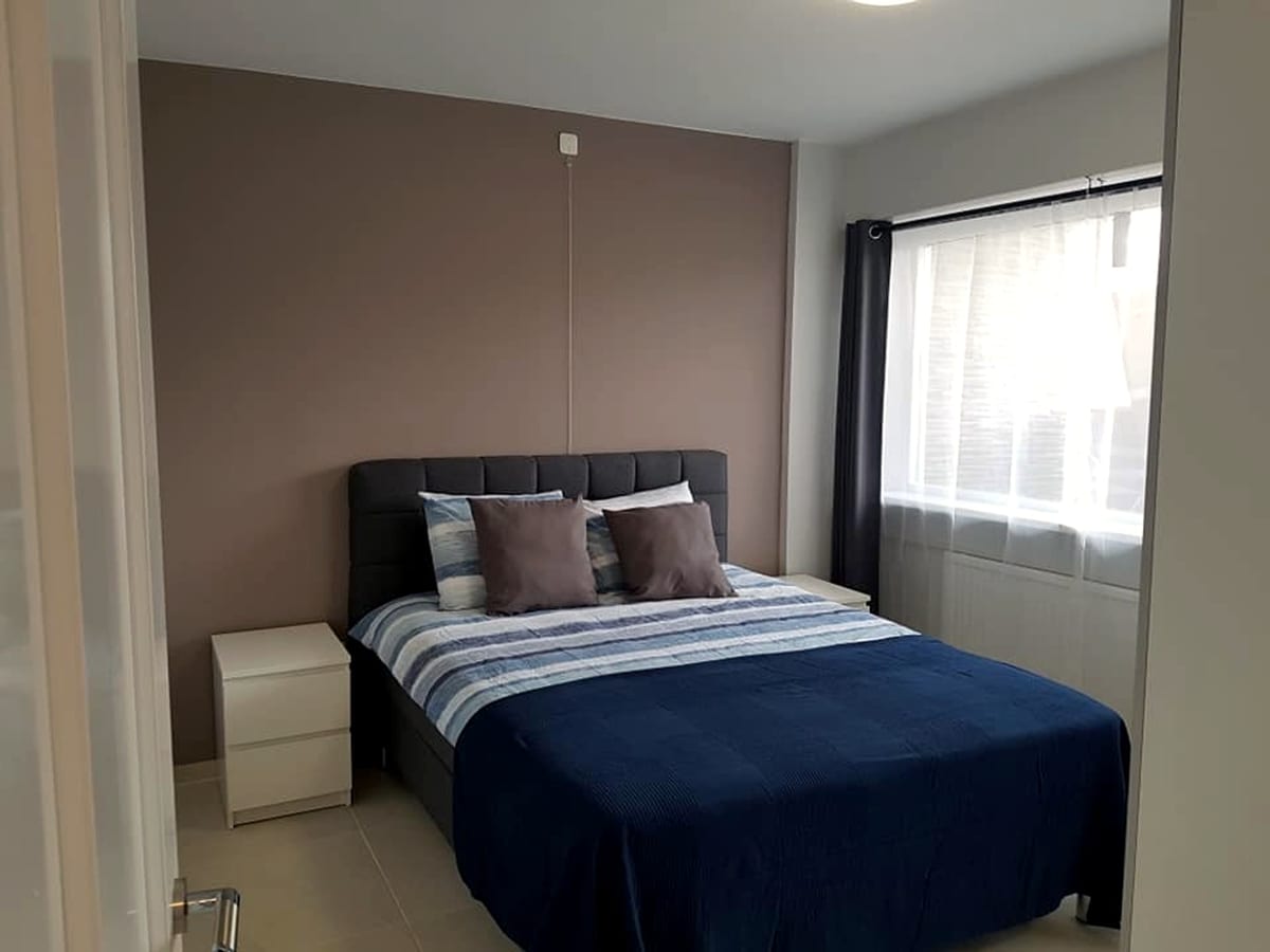 Bright furnished bedroom with double bed beside a large window