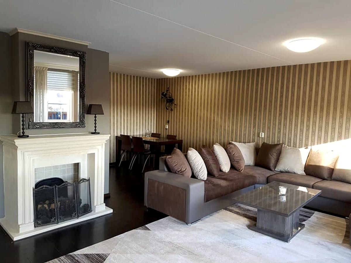 Furnished living room with fireplace, sectional sofa and dining table