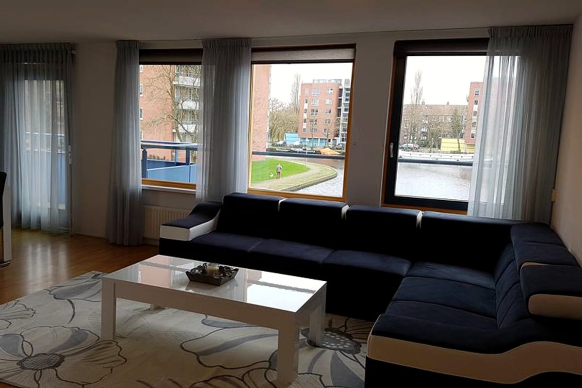 Bright furnished living room with blue sectional sofa and canal view